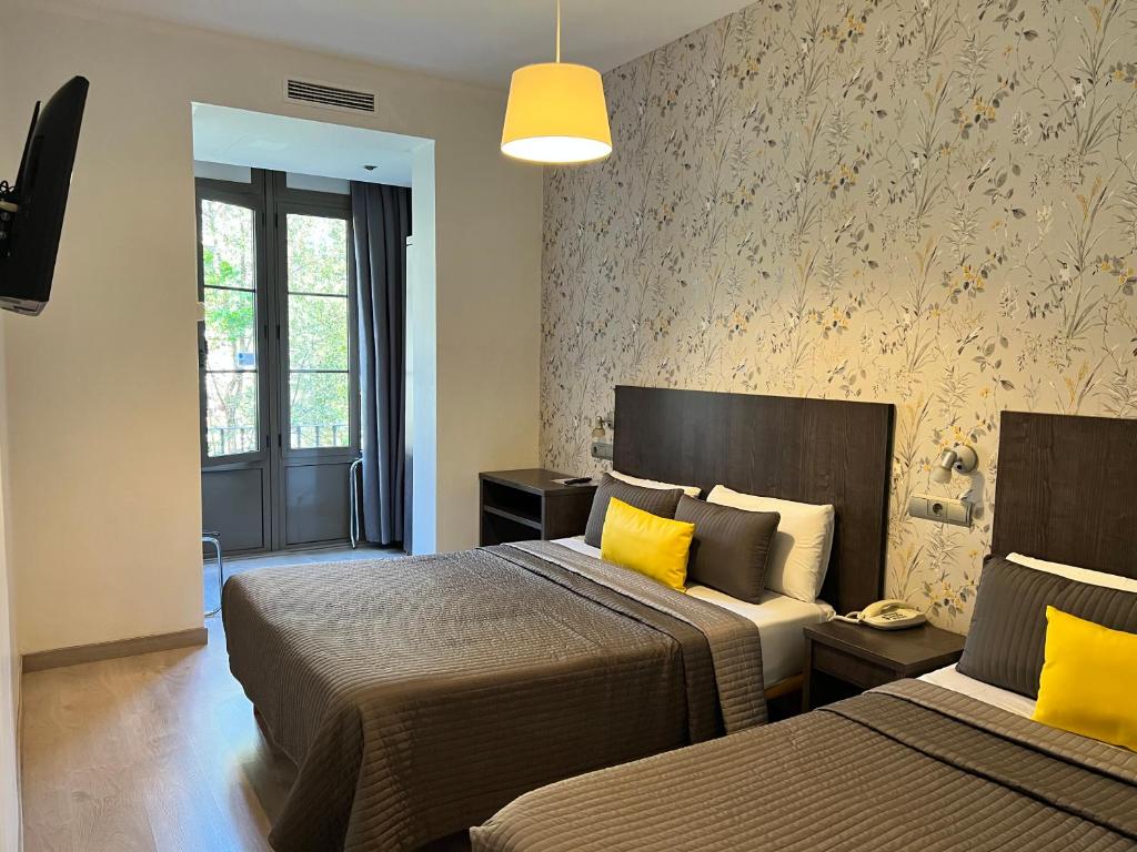 
a hotel room with two beds and two lamps at CIUDAD CONDAL Hostal - Paseo de Gracia in Barcelona

