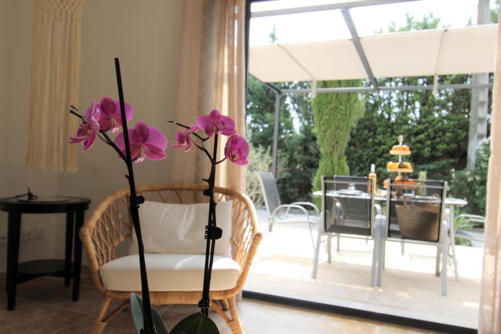 a vase with purple flowers in front of a living room at Les Bastidons de l'Isle - Le Seguret - 3 étoiles in LʼIsle-sur-la-Sorgue