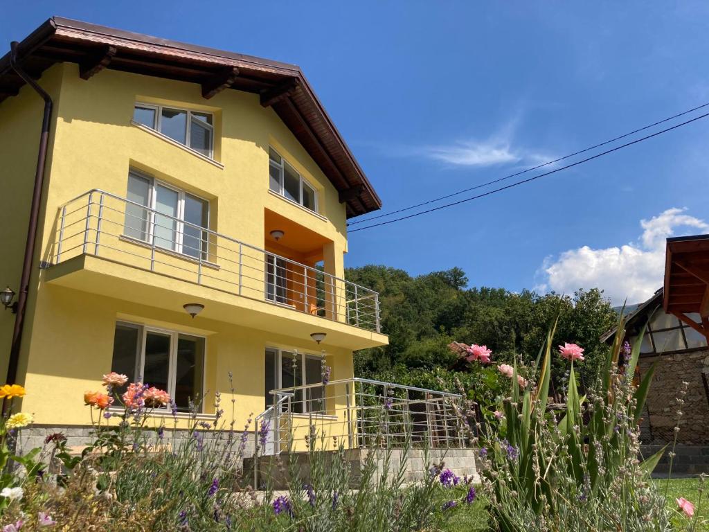 een geel huis met een balkon en bloemen bij Villa Rosa in Krayni Dol