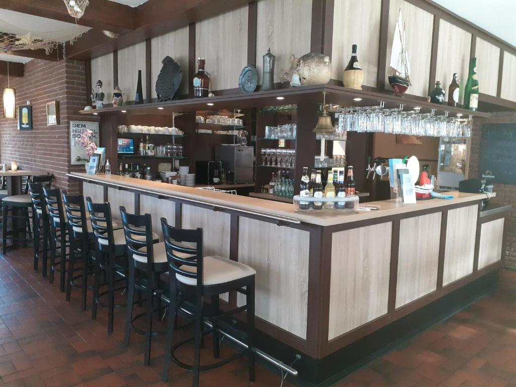 eine Bar mit Stühlen und einer Theke in einem Restaurant in der Unterkunft Weinhaus Hotel in Norddeich