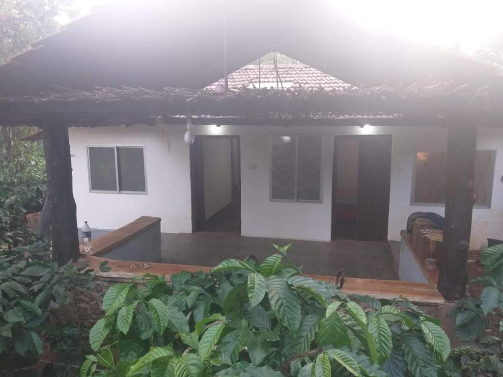 a house with a covered porch in the rain at Durf green in Madikeri