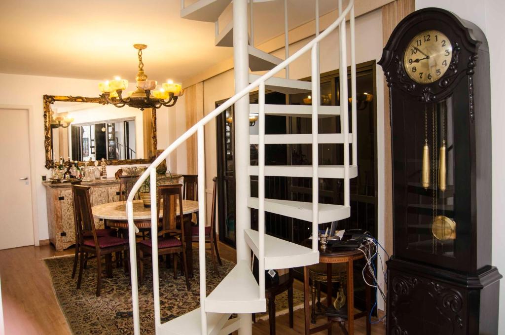 a white spiral staircase in a dining room with a clock at Alto Leblon in Rio de Janeiro