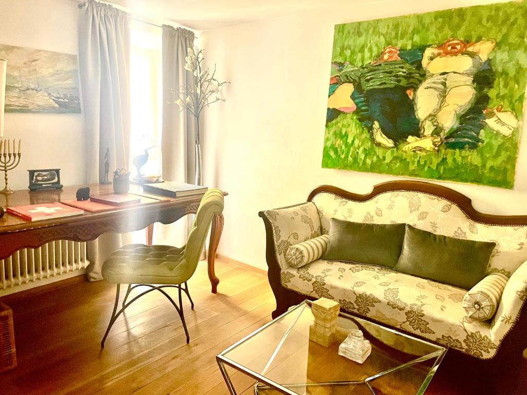 sala de estar con sofá, escritorio y pintura en Elegantes Haus in der Altstadt Caslano en Caslano