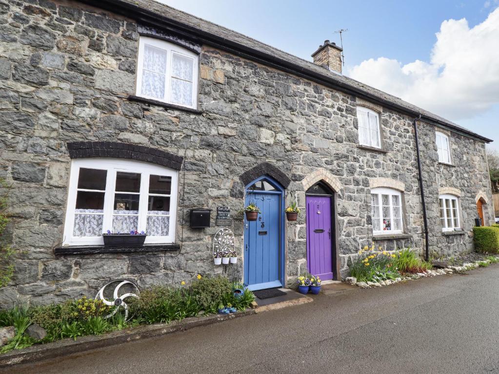 a stone house with blue and purple doors at Coed Y Glyn in Bala