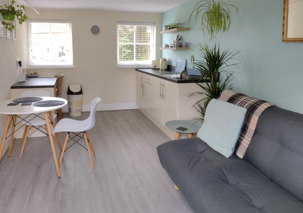 a living room with a couch and a table and a kitchen at The Annexe in Hawkedon