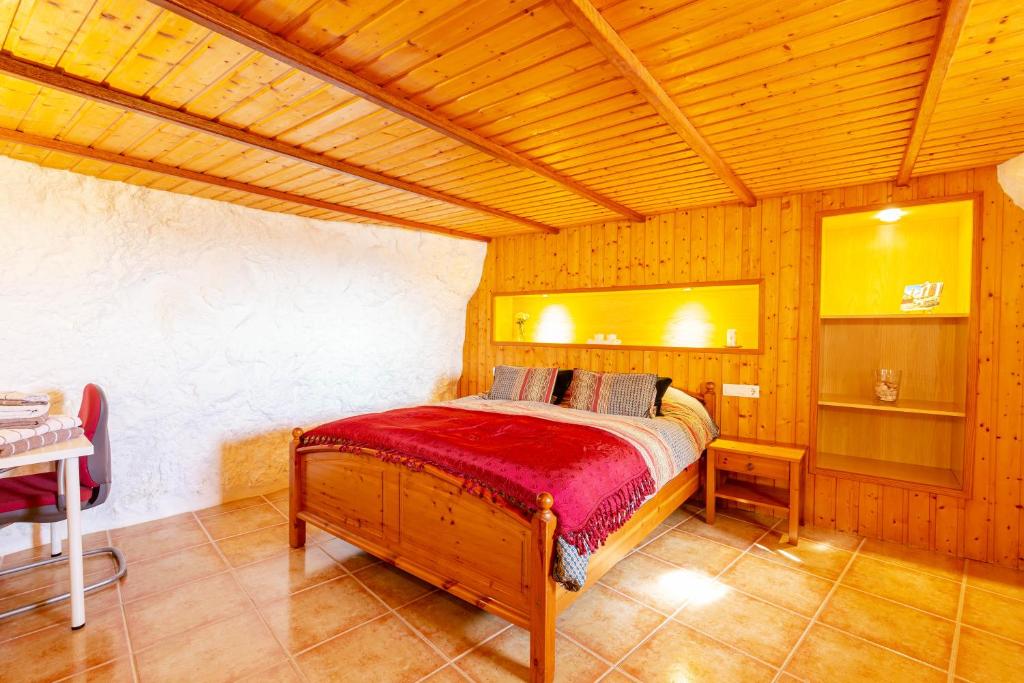 um quarto com uma cama num quarto de madeira em La Cueva de Tito-Casa Cueva en plena naturaleza em Santa Brígida