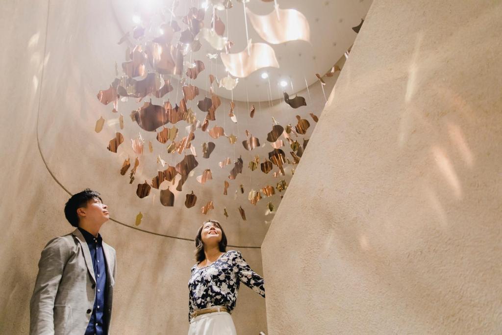 a man and a woman looking up at a chandelier at Dhawa Yura Kyoto - Banyan Group in Kyoto