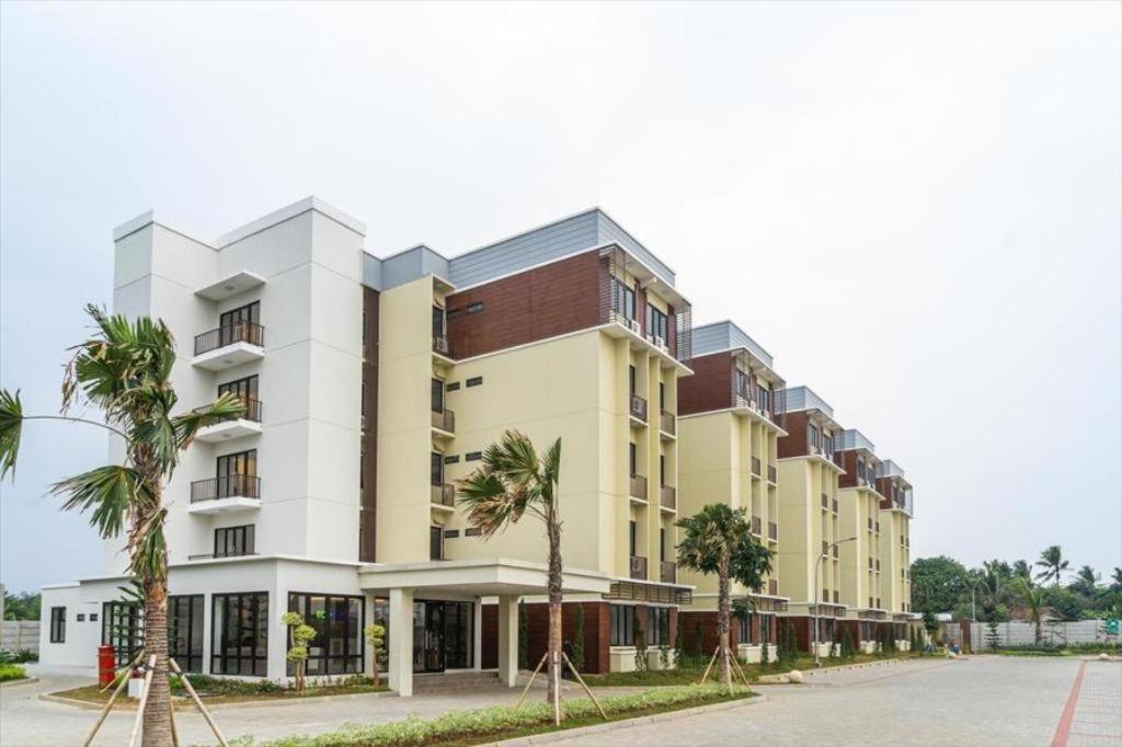 a large building with palm trees in front of it at Apartemen MAJ at Ecohome Citra Raya in Nalagati