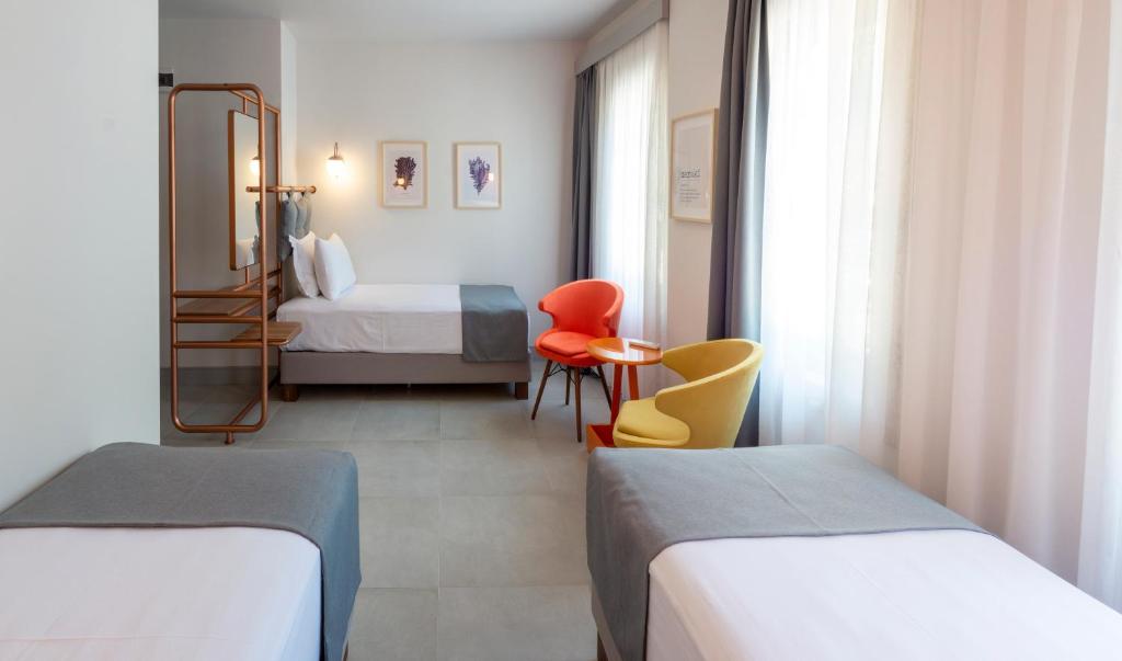 um quarto de hotel com duas camas e uma cadeira vermelha em Meraki Bozcaada em Bozcaada