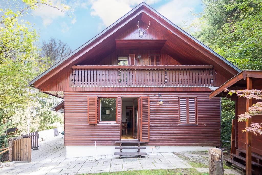 a small red house with a porch and a balcony at Panoramic Forest Chalet Bled Lake View in Bled
