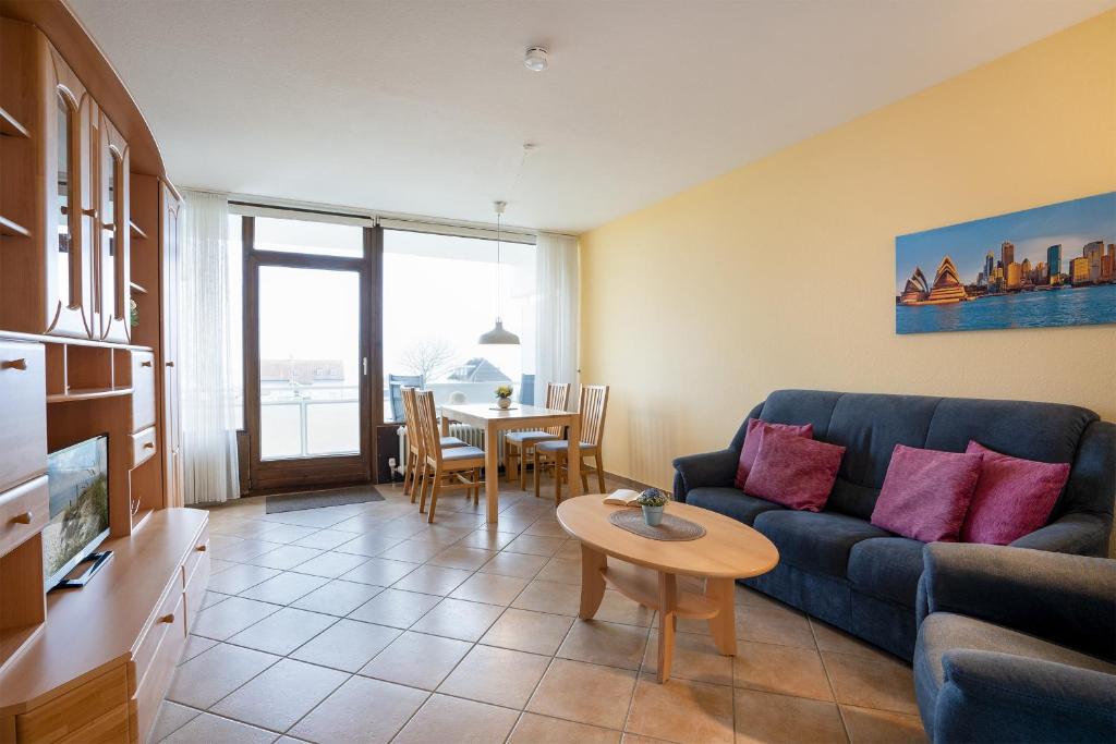 een woonkamer met een blauwe bank en een tafel bij Haus Fernsicht Wohnung 13 in Kellenhusen