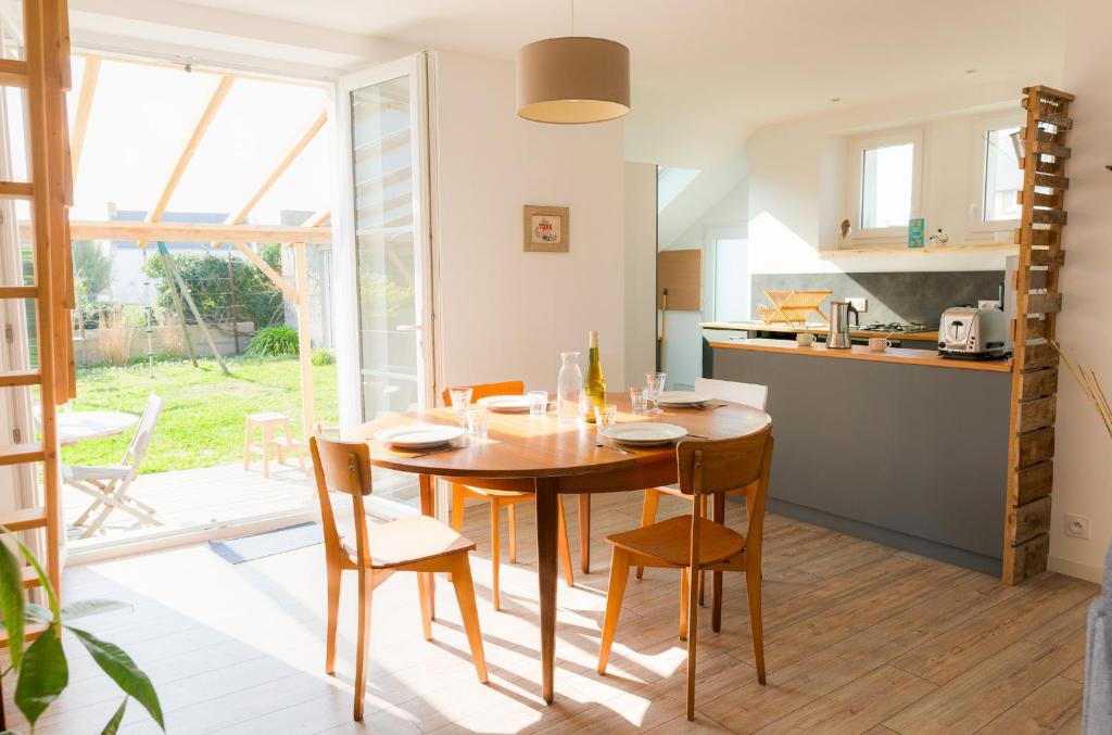 une cuisine et une salle à manger avec une table et des chaises en bois dans l'établissement Vacances en famille a 250m de la mer a Penmarch, à Penmarcʼh