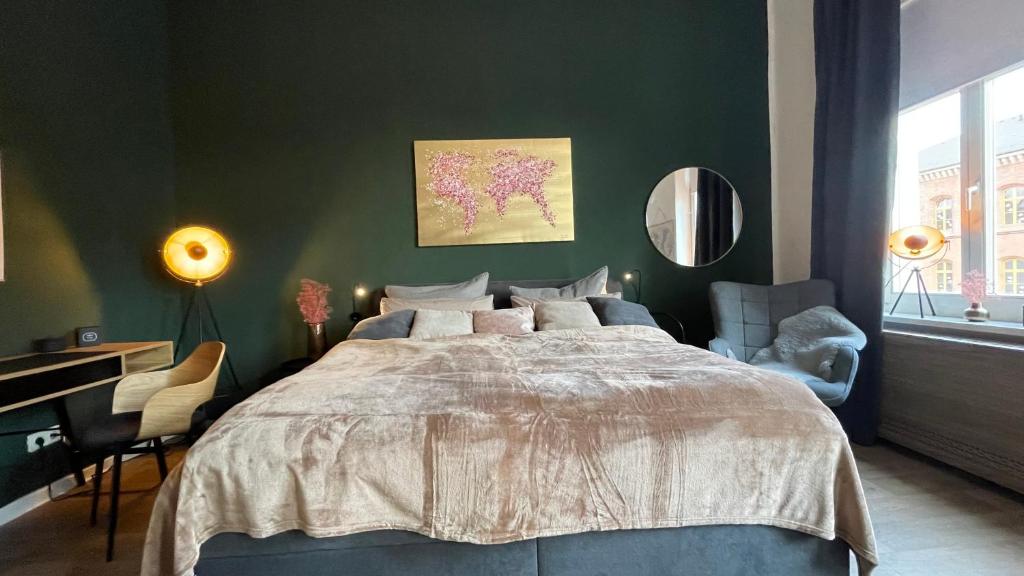 ein Schlafzimmer mit einem großen Bett und einer grünen Wand in der Unterkunft Studio 11 in Torgau