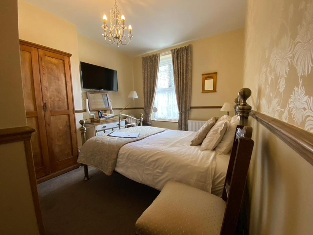 a bedroom with a bed and a chandelier at Rowan Tree Guest House in Keswick