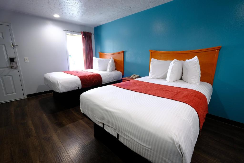 two beds in a hotel room with blue walls at M Star Hotel Searcy in Searcy