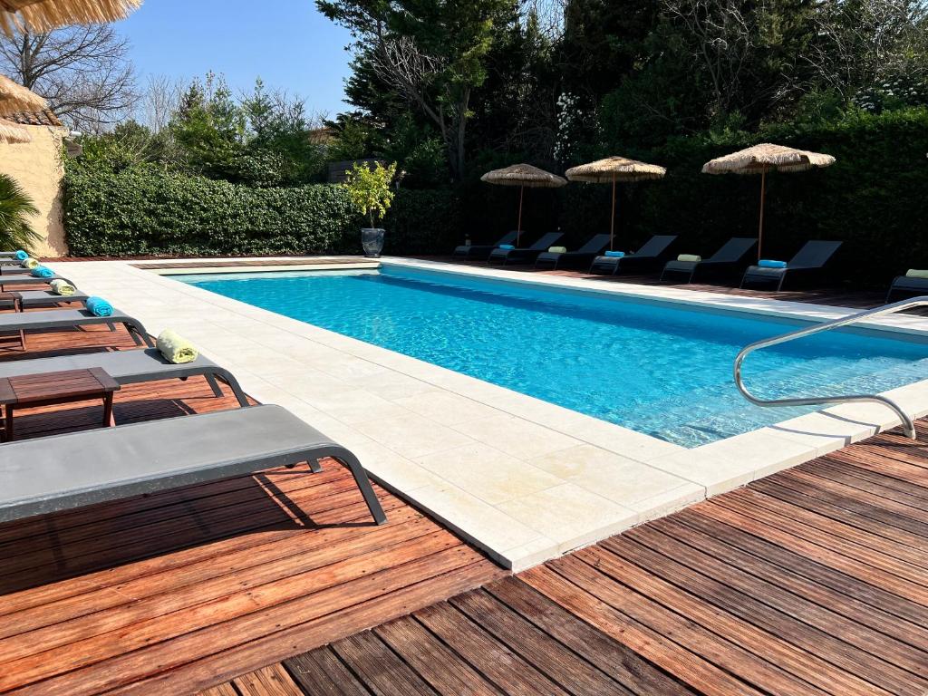 a swimming pool with chairs and umbrellas on a deck at Résidence Les Sources in Saint-Rémy-de-Provence