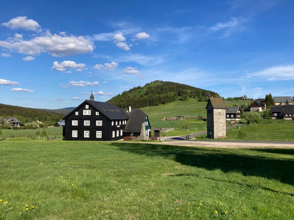 a black house in a field of green grass at Pyramida - Jizerka in Jizerka