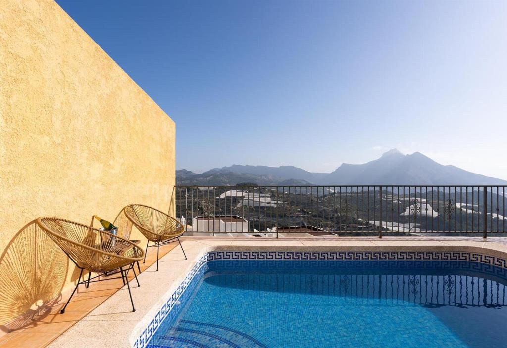 einen Pool mit zwei Stühlen neben einem Gebäude in der Unterkunft Casa Linda Vista Altea Costa Blanca in Callosa d'en Sarrià