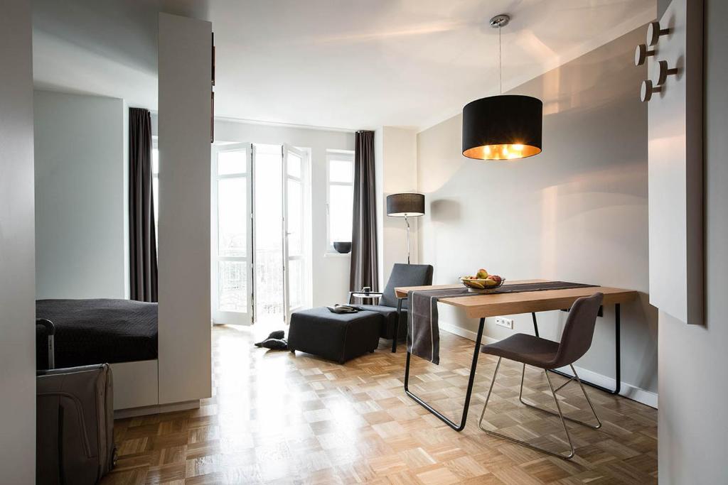 a living room with a table and a bedroom at SMARTments business Hamburg Aussenalster in Hamburg