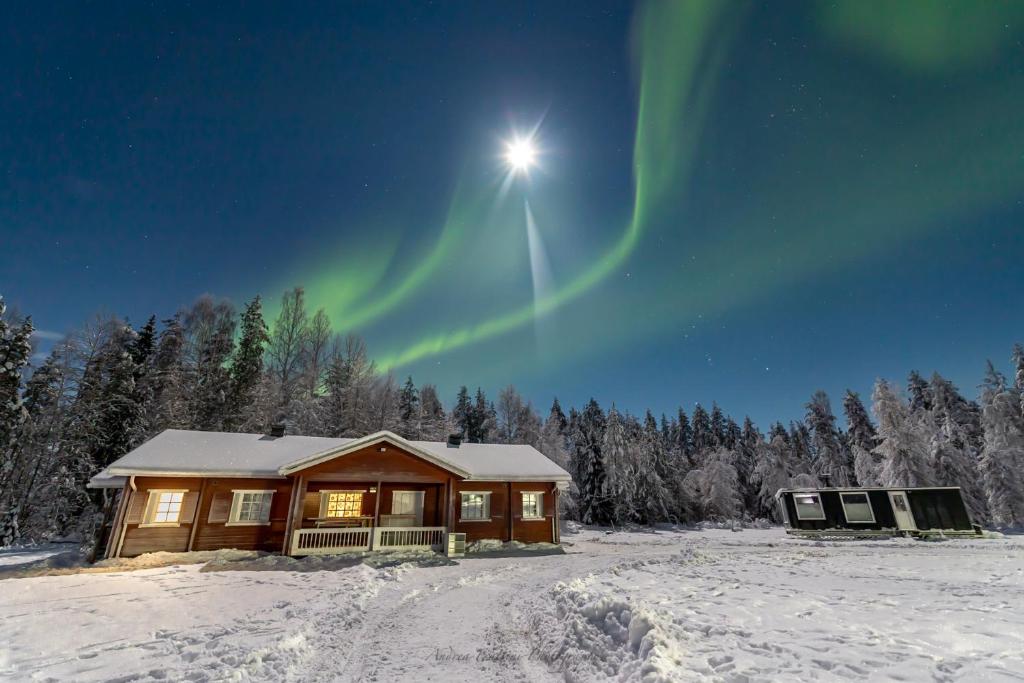 a log cabin with the aurora in the sky at Old Pine Husky Lodge in Sompujarvi