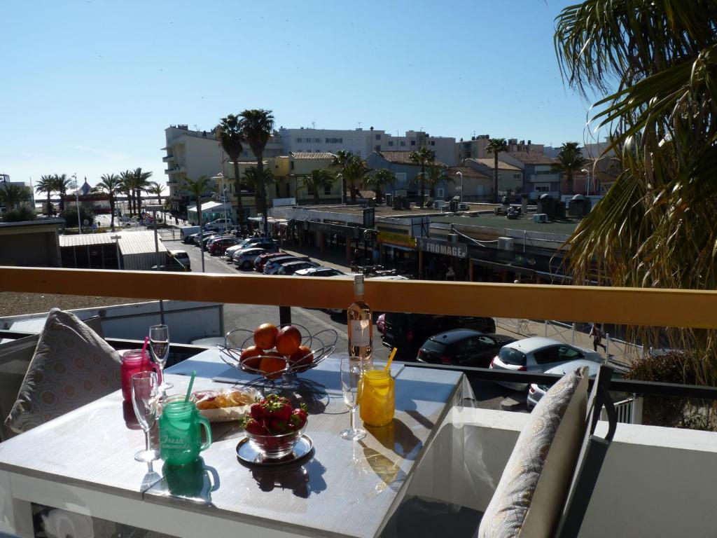 uma mesa com comida e bebidas numa varanda em Sol-y-Days Cigales de mer, studios bien équipés et climatisés, en centre-ville à 150m de la plage em Le Grau-du-Roi