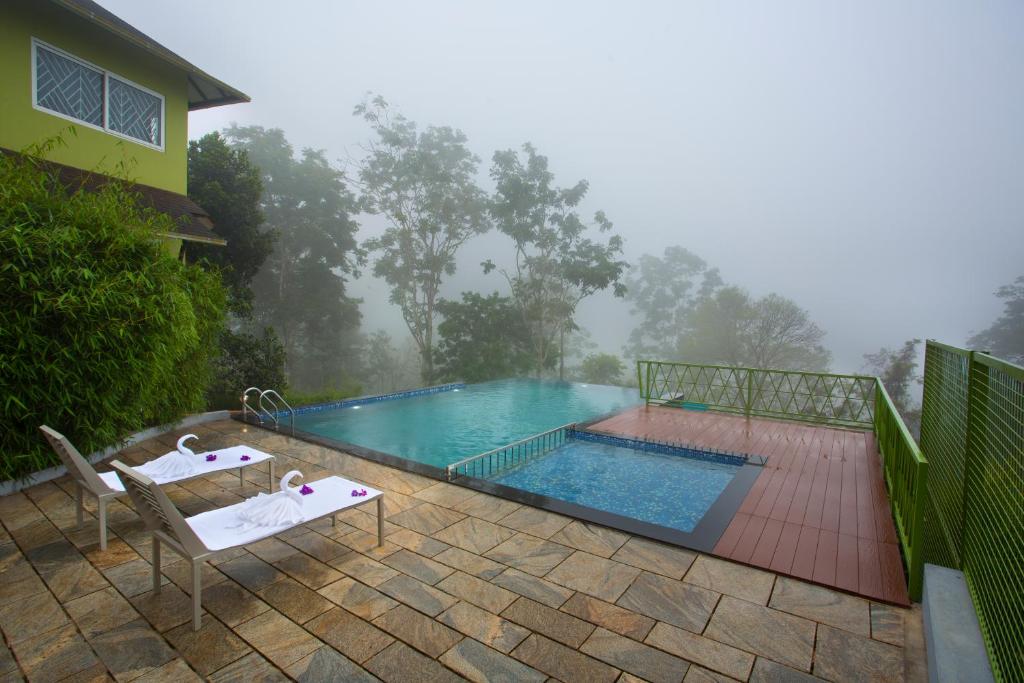 a swimming pool with two chairs next to a house at Amrezy Luxury Resort and Spa, Wayanad in Vythiri