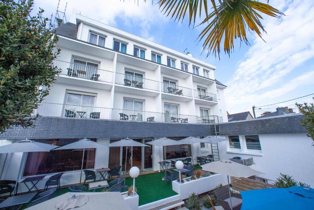 - une vue sur l'extérieur d'un hôtel avec des tables et des parasols dans l'établissement Hotel les Alignements, à Carnac