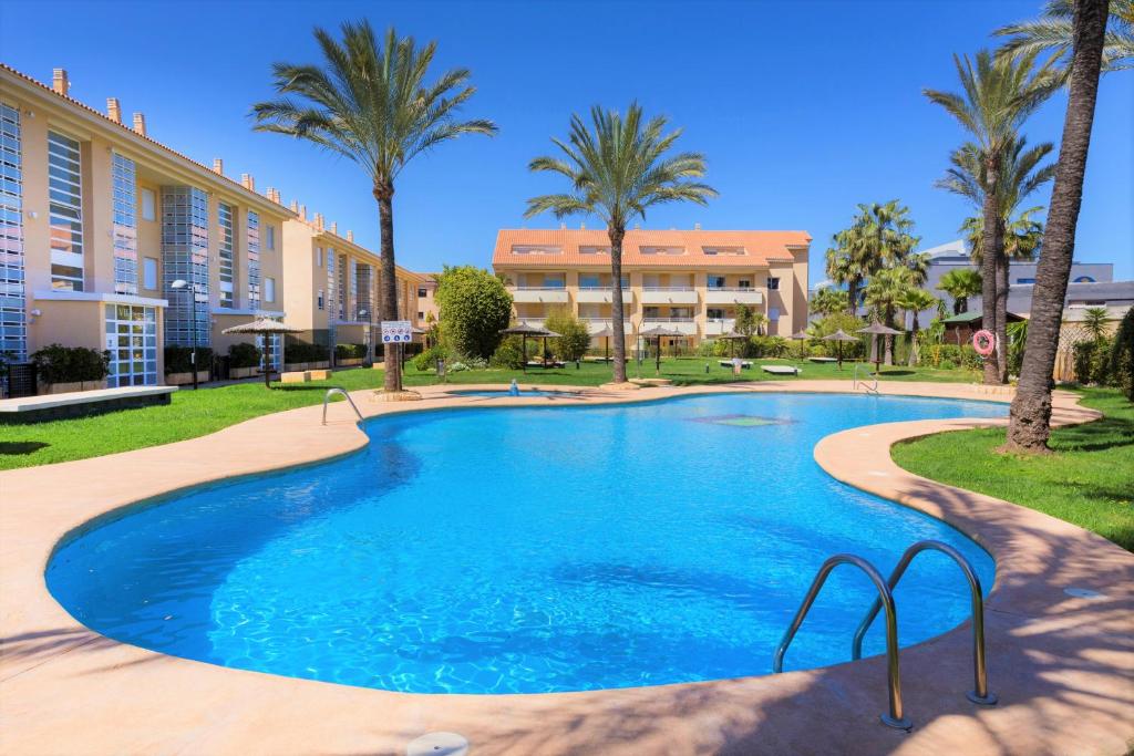 een groot zwembad in een resort met palmbomen bij Veranda Golden Beach II Apartment Javea Arenal in Jávea