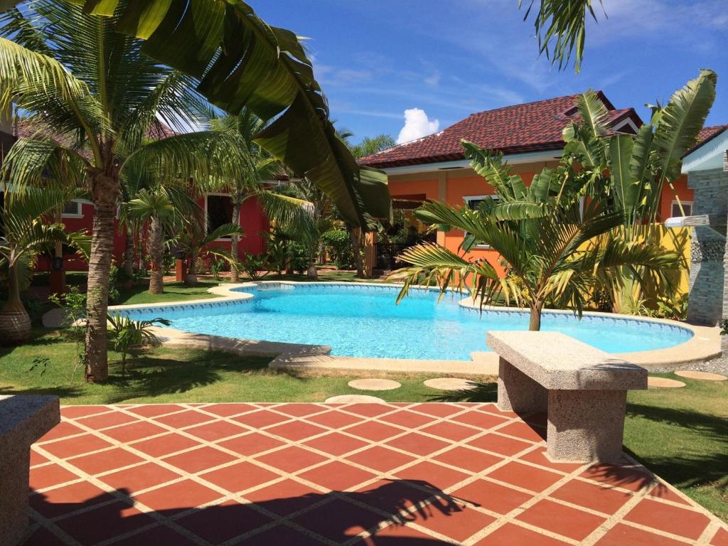 a swimming pool with a bench next to a house at Alona's Coral Garden Resort (Adult-Only) in Panglao Island