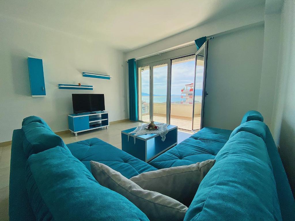 a living room with a blue couch with a view of the beach at Saranda Terraces Apartment Rentals in Sarandë