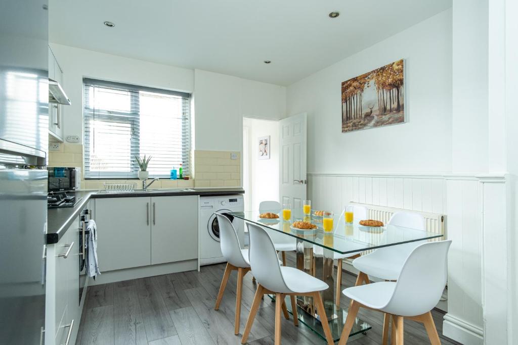 a white kitchen with a table and chairs in it at Enfield House in Coventry
