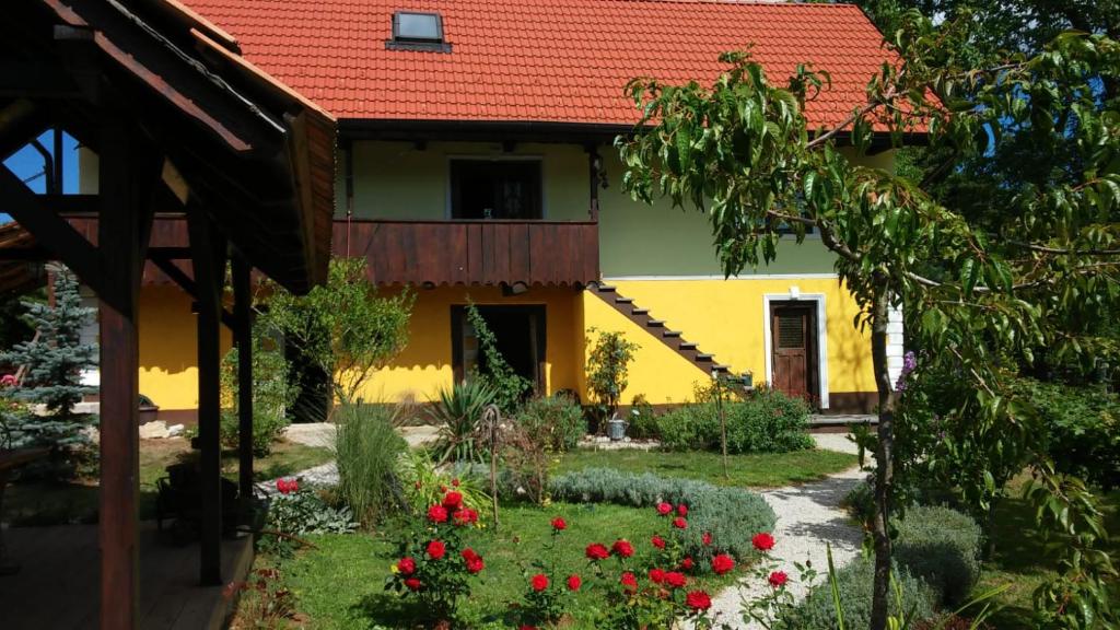 a yellow house with a red roof and red flowers at Kuća za odmor Sichelberg in Žumberak