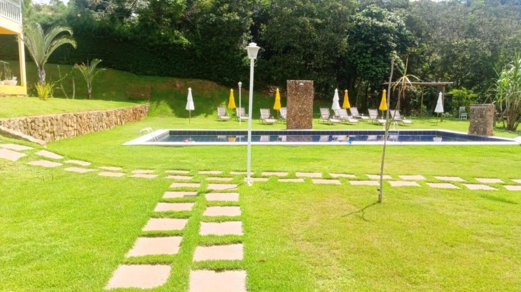 a garden with a swimming pool with umbrellas at Pousada Mendonça in Jaboticatubas