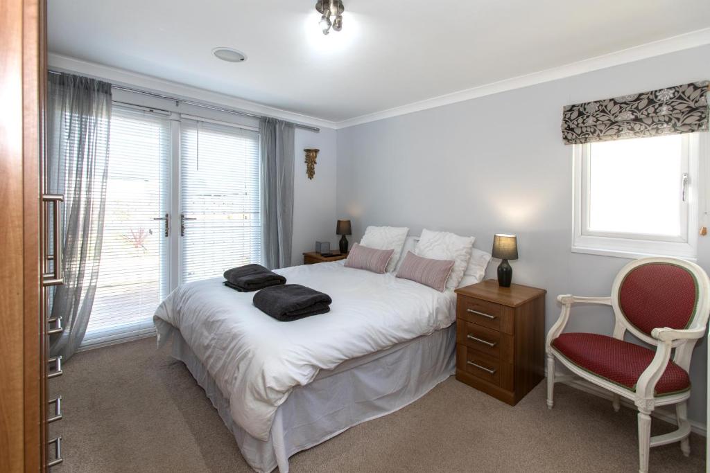 a bedroom with a bed and a chair and a window at Carnoustie Dreams in Wisbech