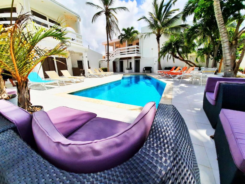 a pool with purple chairs next to a building at Bubali Residence in Palm-Eagle Beach