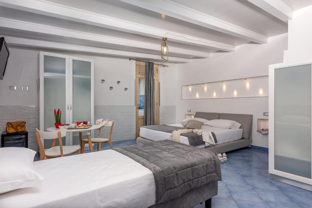 Cette chambre comprend 2 lits et une table. dans l'établissement Albert Rooms & Breakfast, à San Vito Lo Capo