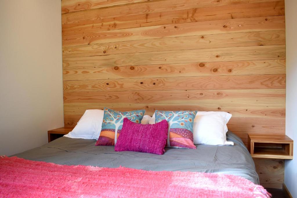 1 dormitorio con 1 cama con pared de madera en Cabaña a pasos del río rodeada de un hermoso entorno nativo natural, en Villarrica