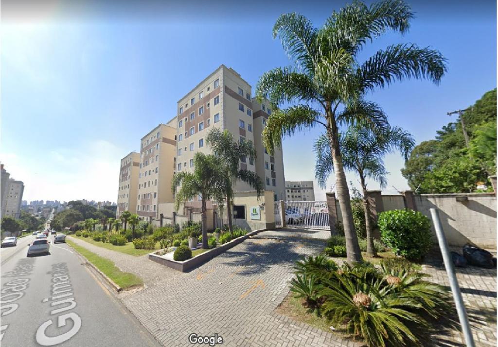 un edificio con palmeras al lado de una calle en Apto em Curitiba perto de tudo, en Curitiba
