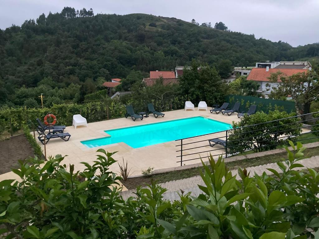 uma piscina com cadeiras e uma montanha ao fundo em Alojamento Casa da Pedra Verde em Vieira do Minho