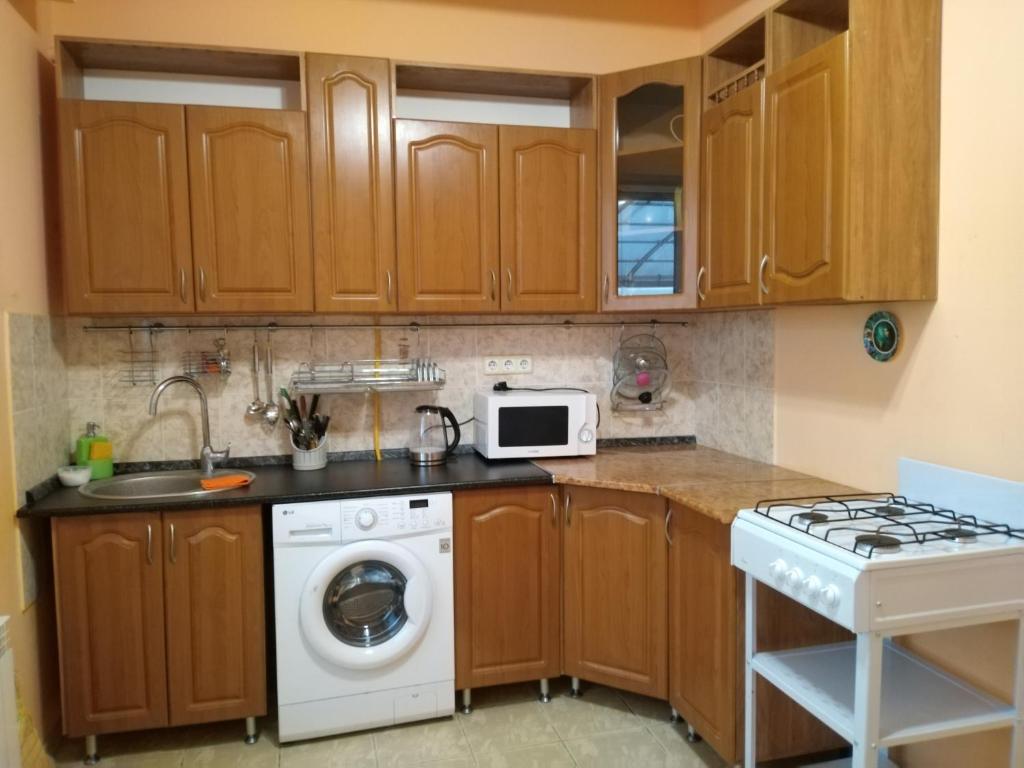 a kitchen with wooden cabinets and a washer and dryer at Дом На Хвойной in Lazarevskoye