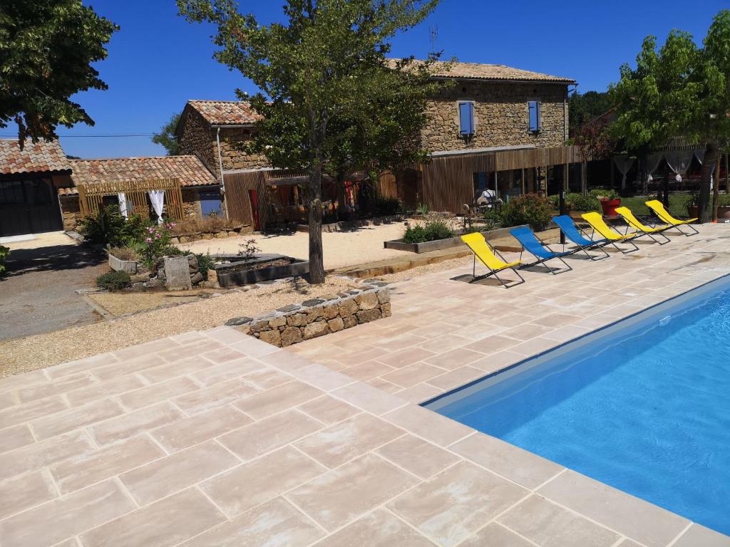 a swimming pool with chairs and a house at Gite Terradou in Planzolles