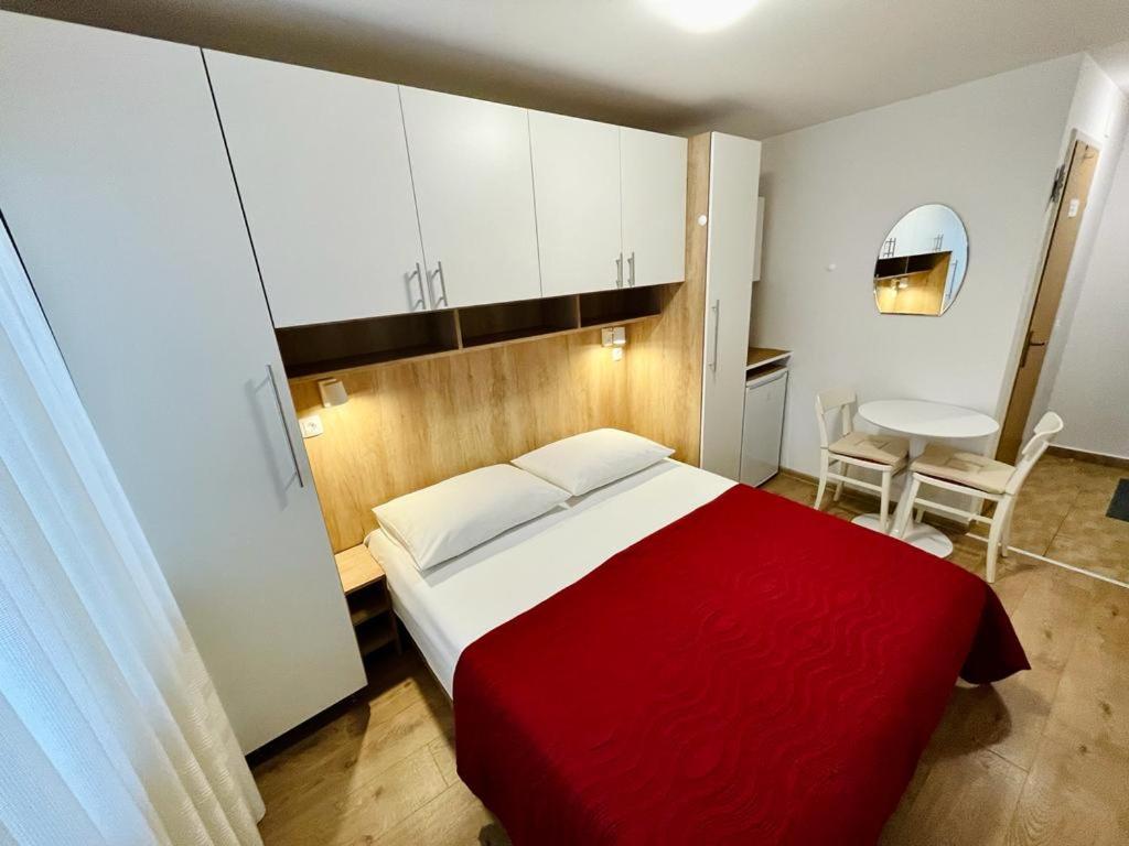 a bedroom with a red and white bed and a table at Guest House Korunić in Korčula