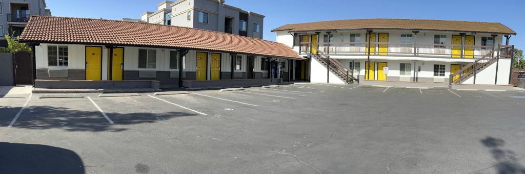 a parking lot in front of a building with yellow doors at Escondido Inn in Escondido