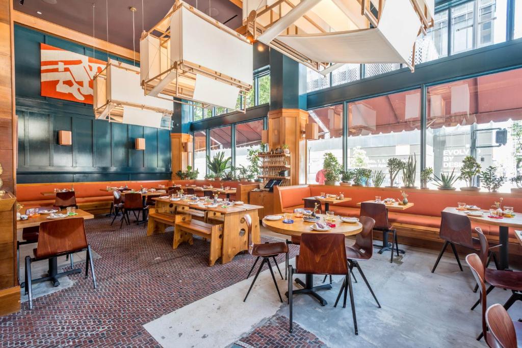a restaurant with wooden tables and chairs and large windows at Freehand Los Angeles in Los Angeles