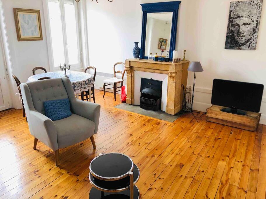 ein Wohnzimmer mit einem Kamin, einem Stuhl und einem TV in der Unterkunft Le Cheylard, appartement spacieux et lumineux in Le Cheylard
