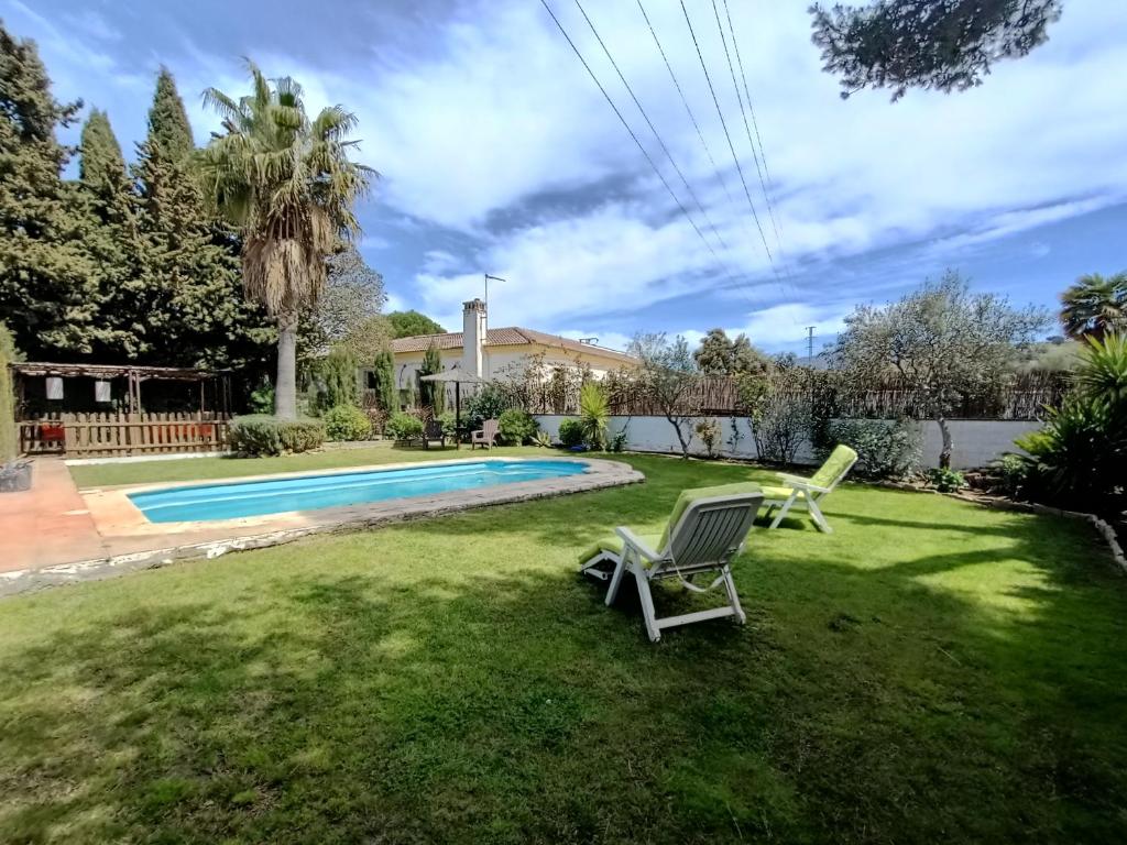 een tuin met 2 ligstoelen en een zwembad bij Casa Rural Ciudad Soñada in Ronda