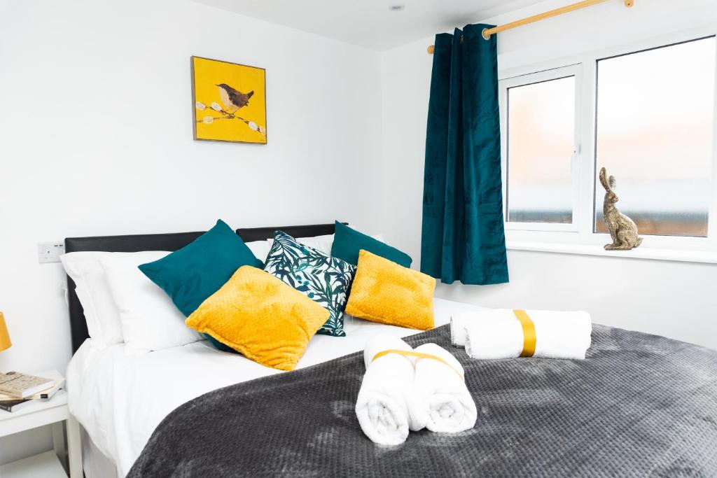 a bedroom with a bed with yellow and blue pillows at Kelston View by Cliftonvalley Apartments in Bristol