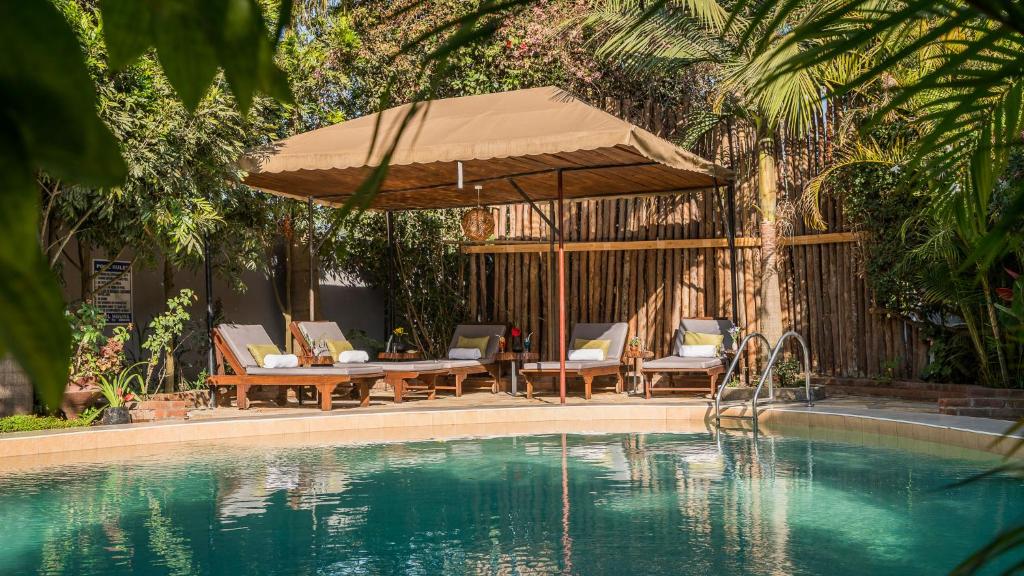 uma piscina com uma mesa e cadeiras e um guarda-sol em Villa Arumeru em Arusha