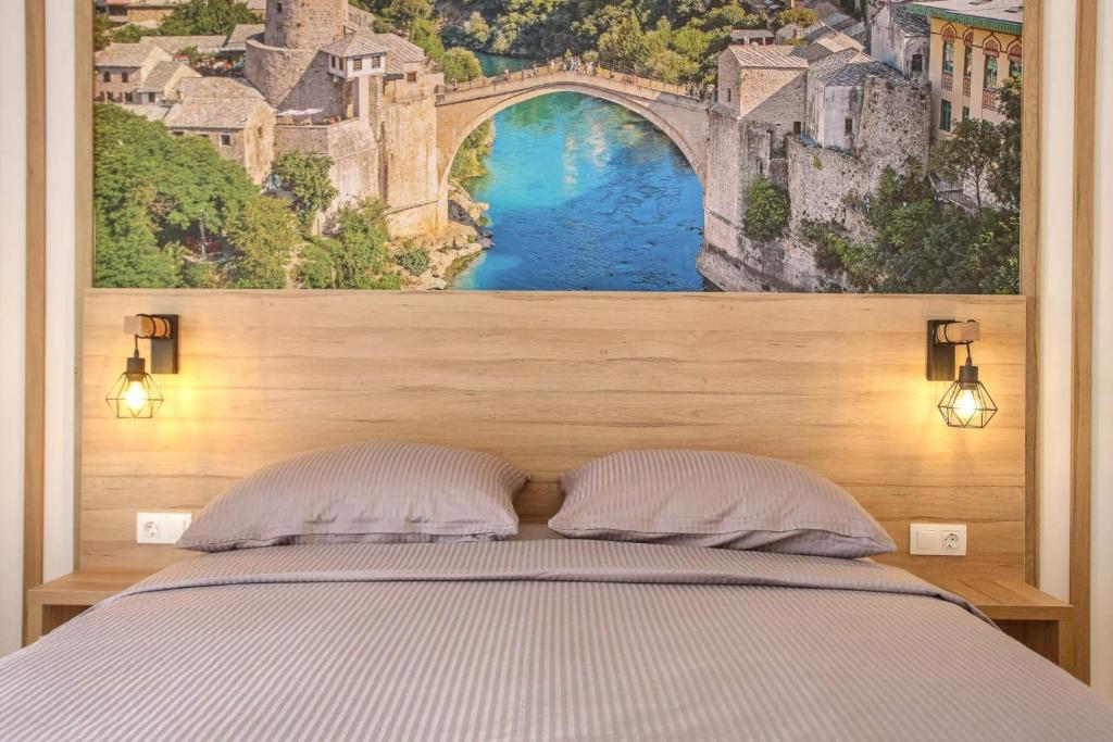 een slaapkamer met een schilderij van een brug boven een bed bij Apartments & Rooms ARCH in Mostar