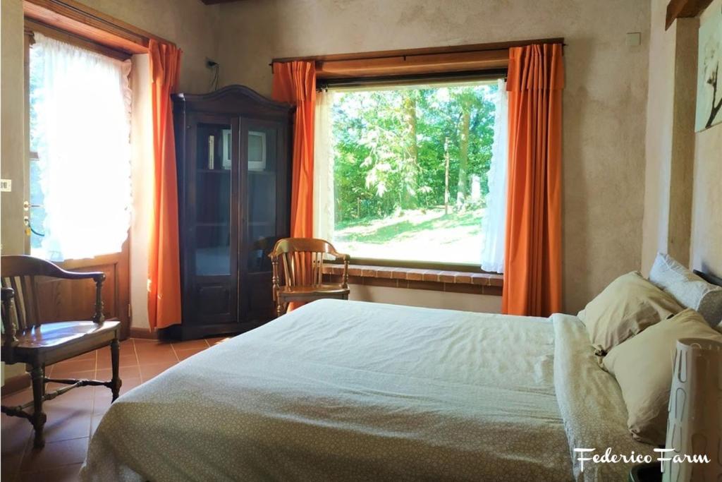 Schlafzimmer mit einem Bett und einem Fenster mit orangefarbenen Vorhängen in der Unterkunft Agriturismo La Casa del Sarto in Pontremoli